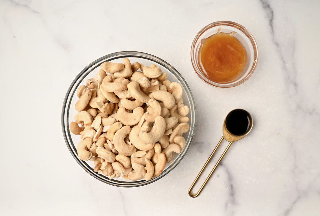 A clear glass bowl full of cashews
