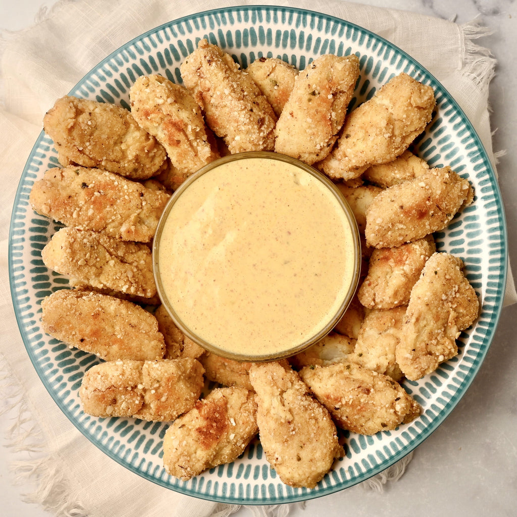 A close up of a plate of homemade cauliflower tots with a small bowl of dipping sauce