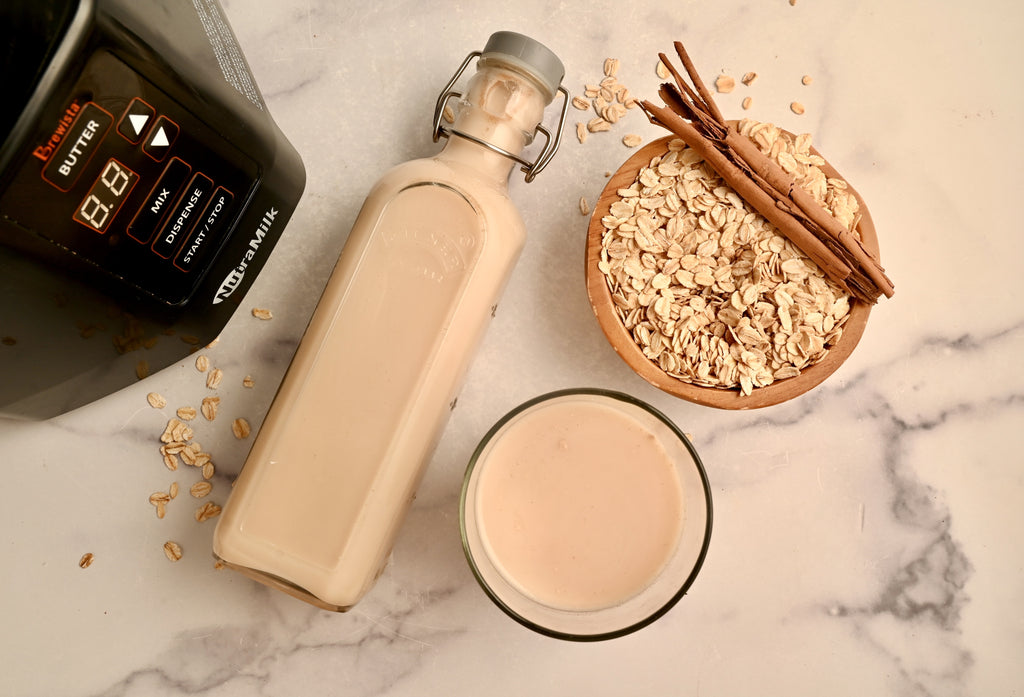 A glass jar filled with oat milk laying on a kitchen counter