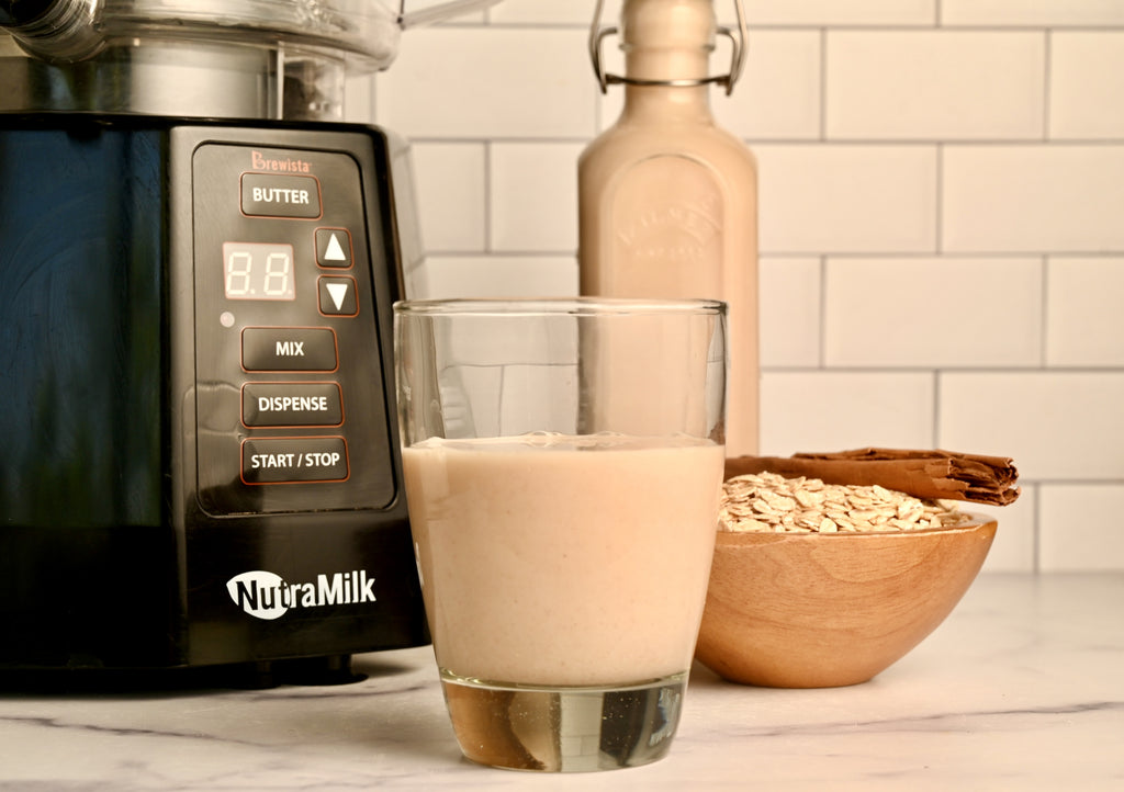 A glass of flavored oat milk in front of The NutraMilk