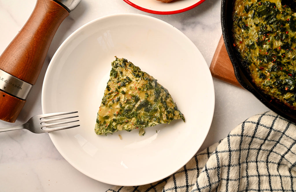 A slice of spinach quiche on a white plate