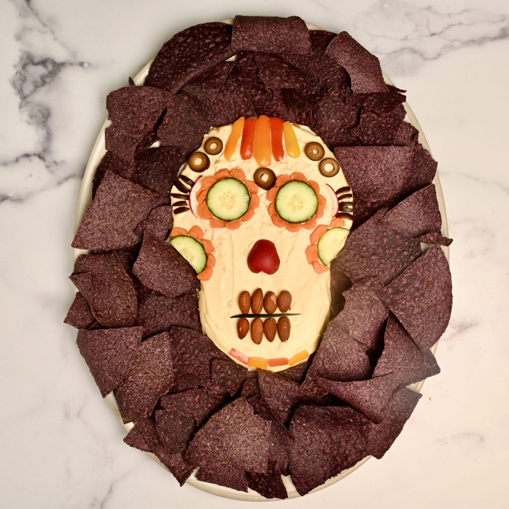 A skeleton hummus dip surrounded by blue tortilla chips