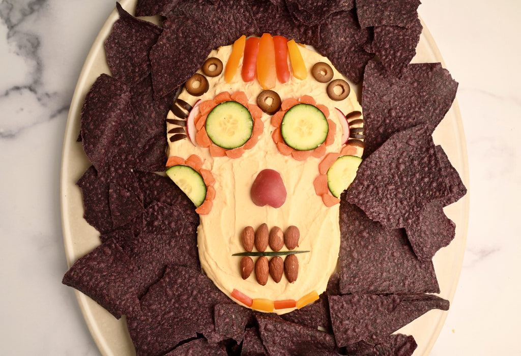 A skeleton hummus dip surrounded by blue tortilla chips