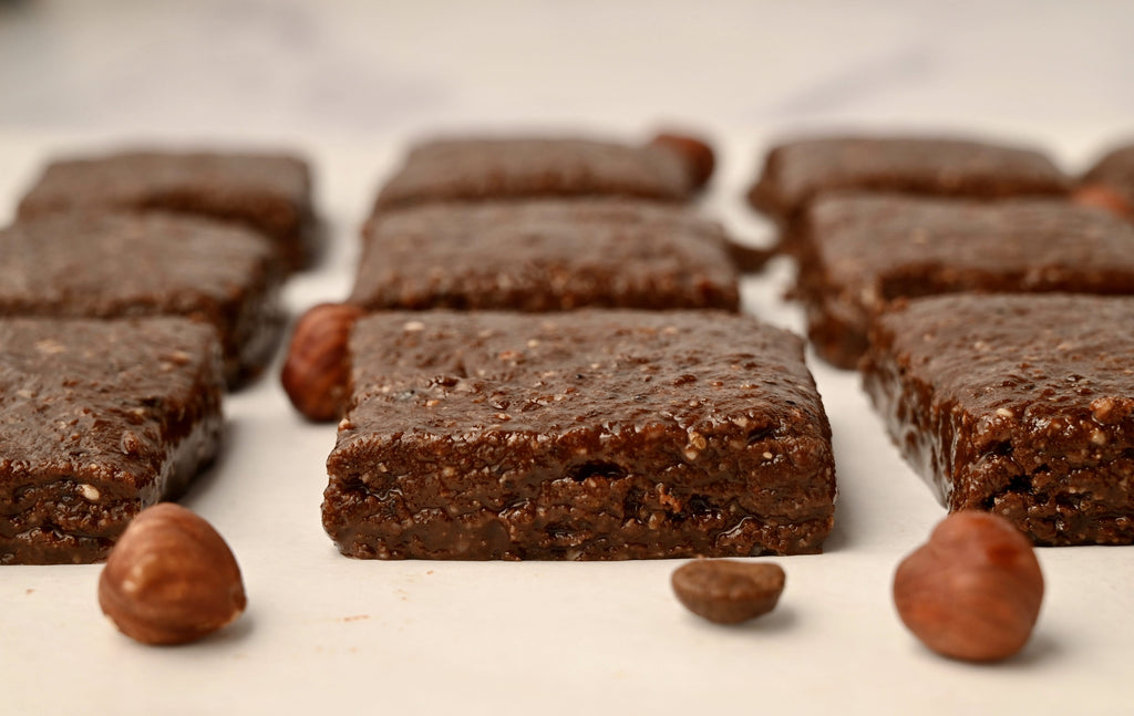 Homemade maca coffee energy bars on a white tray with hazelnuts scattered around them