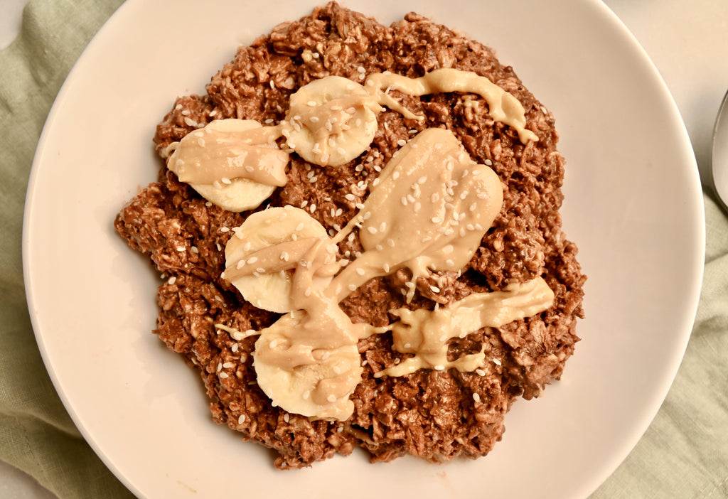 Close up of chocolate overnight oats with banana slices and nut butter