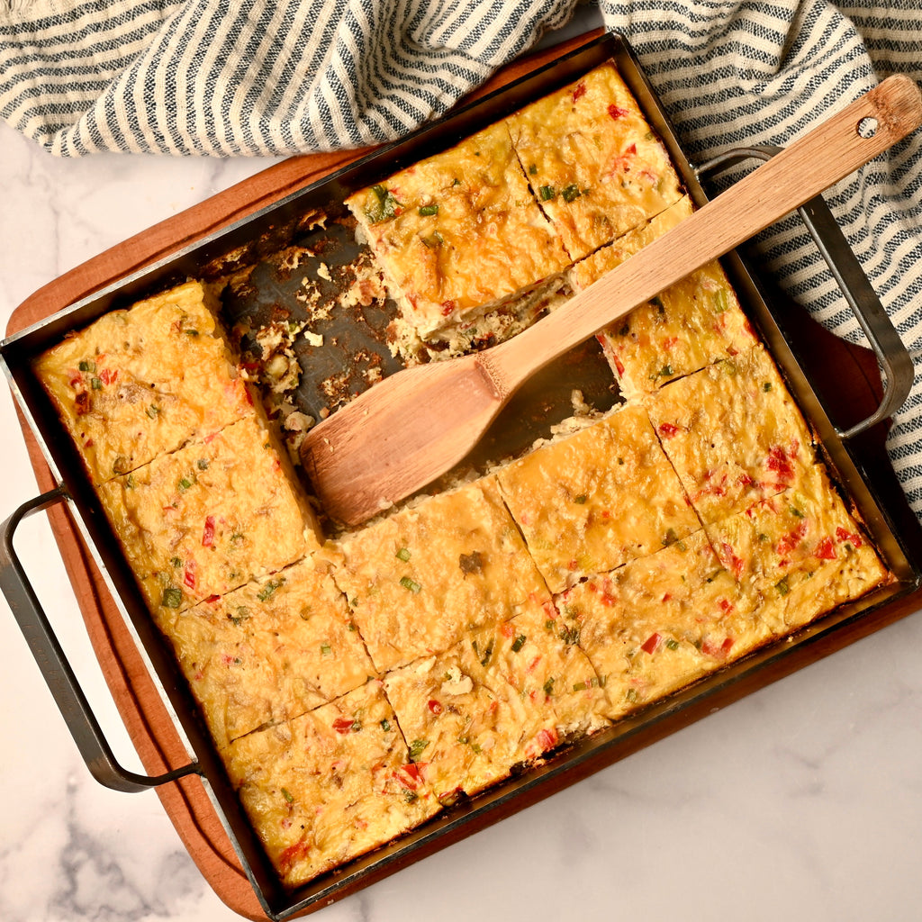 Hashbrown casserole in a square cast iron skillet with slices cut out of it