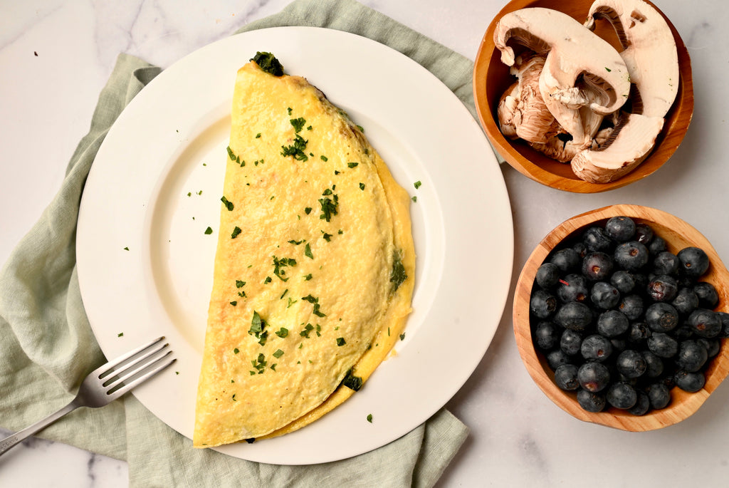 Spinach omelette on a white plate with a fork in next to it