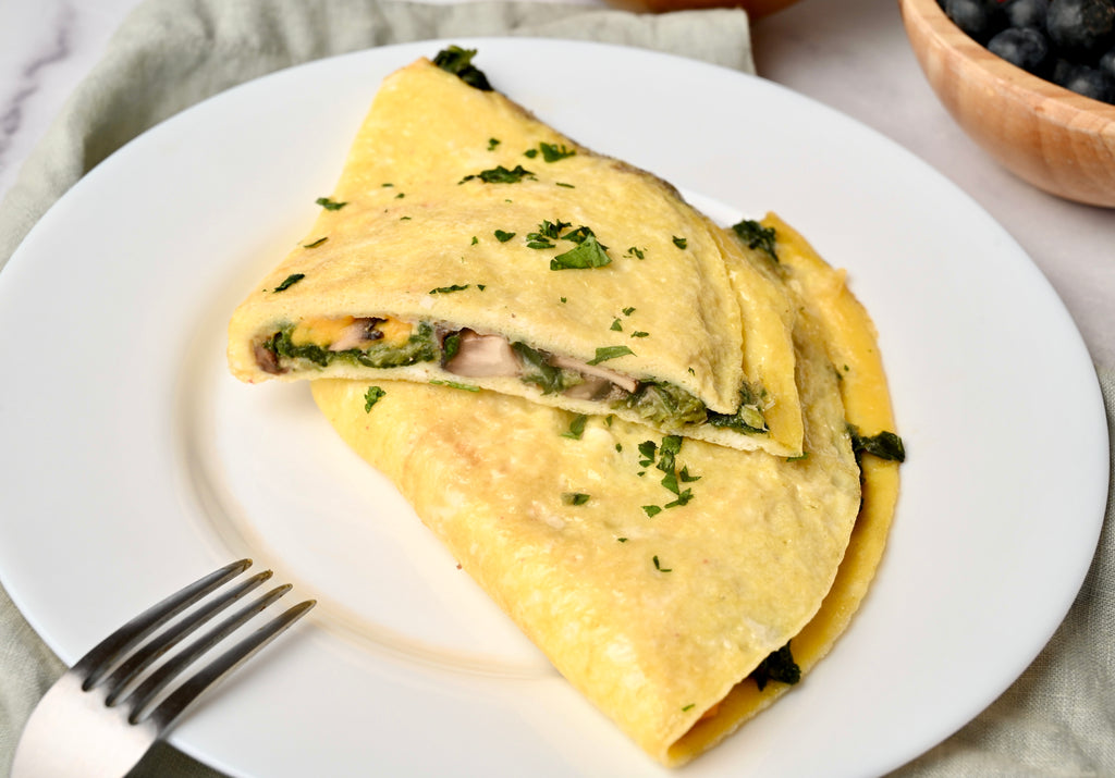 Spinach omelet on a white plate cut open with a fork near it