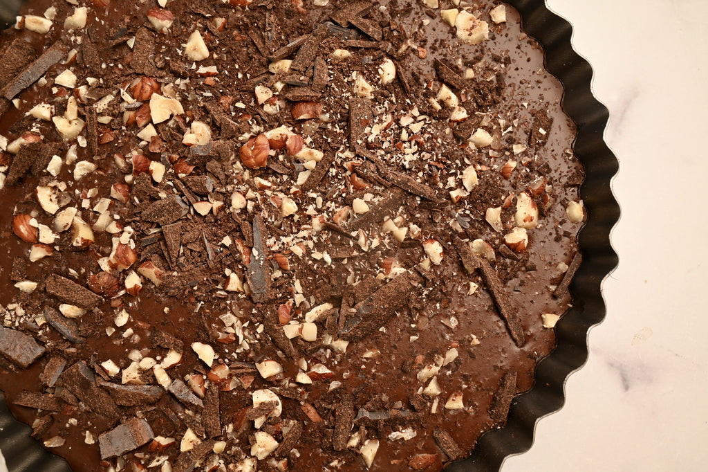 A close up of crushed hazelnuts on a chocolate tart