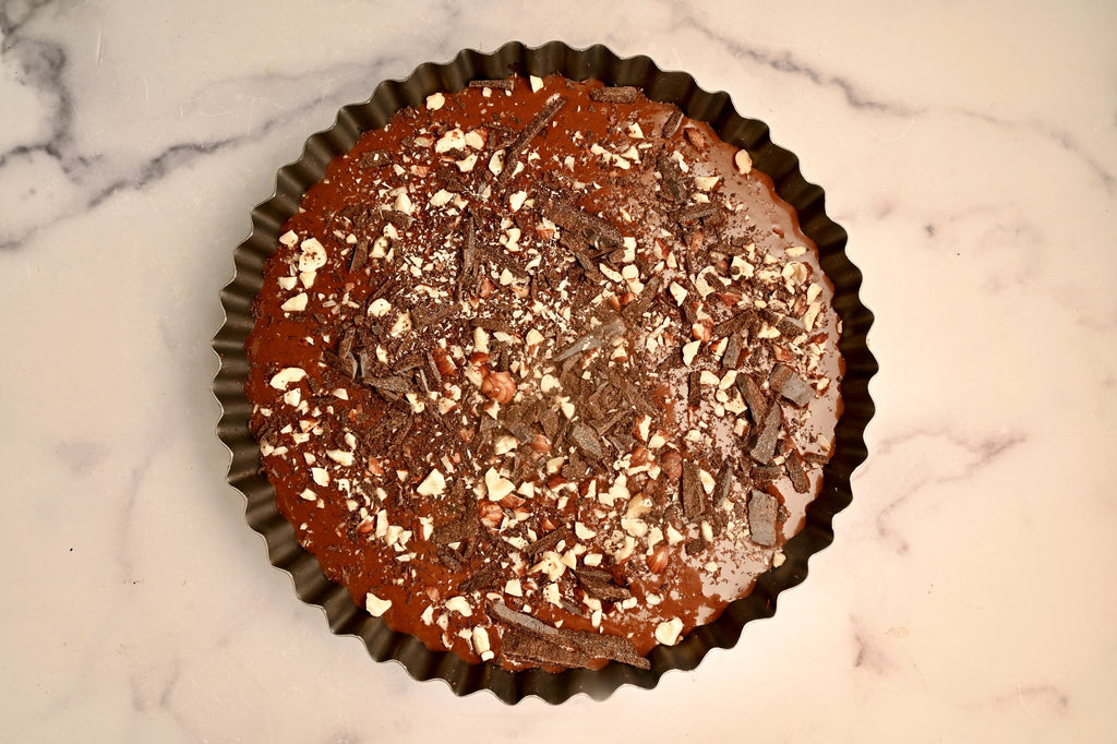 An overview of a chocolate tart with crushed hazelnuts on top