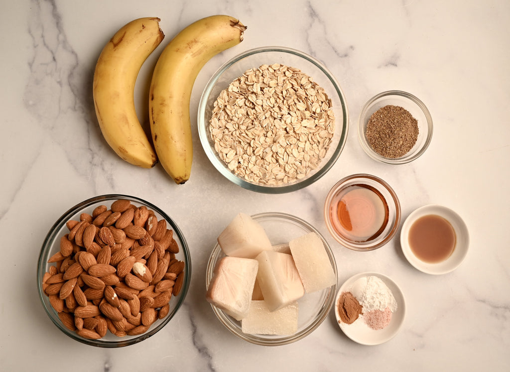 Raw almonds and other oatmeal ingredients in clear glass bowls on a kitchen counter