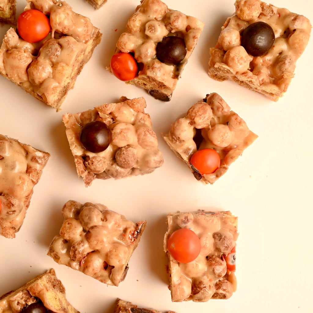 A close of peanut butter cereal bars with black and orange M and M candies