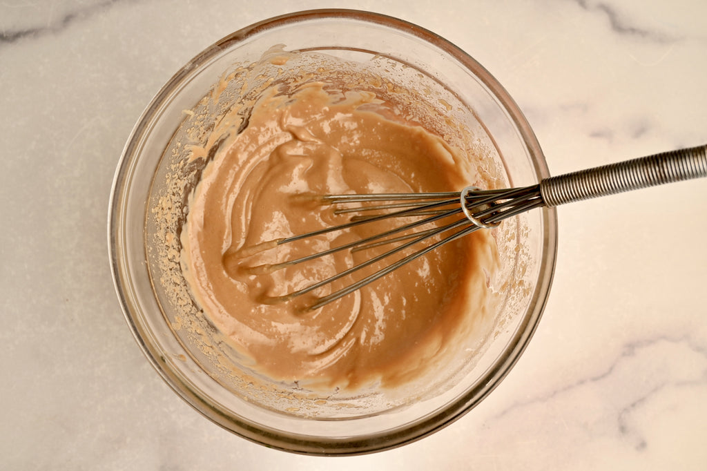 A clear glass mixing bowl filled with a homemade peanut sauce