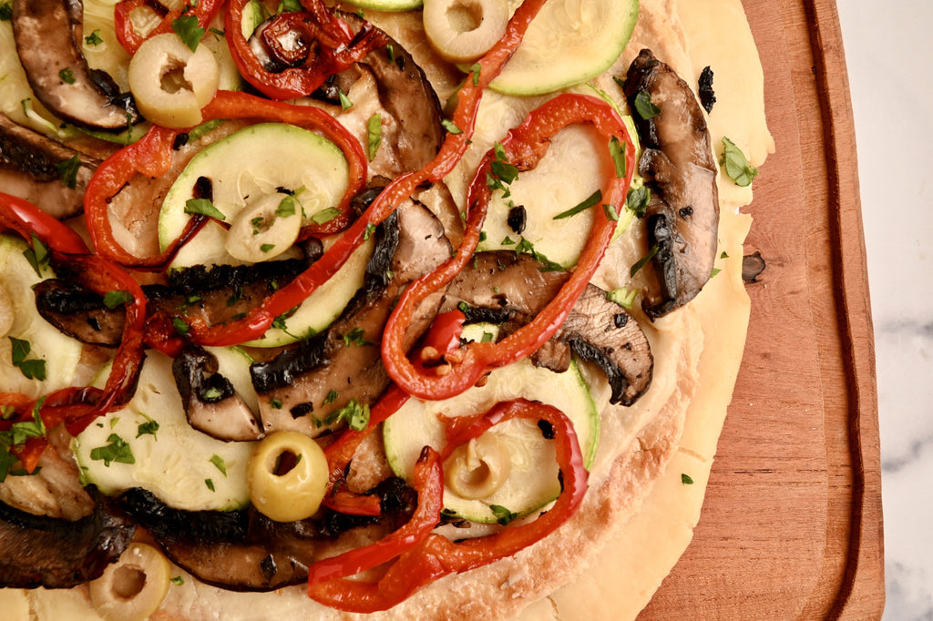 A close up of a Bianca pizza with veggies on top