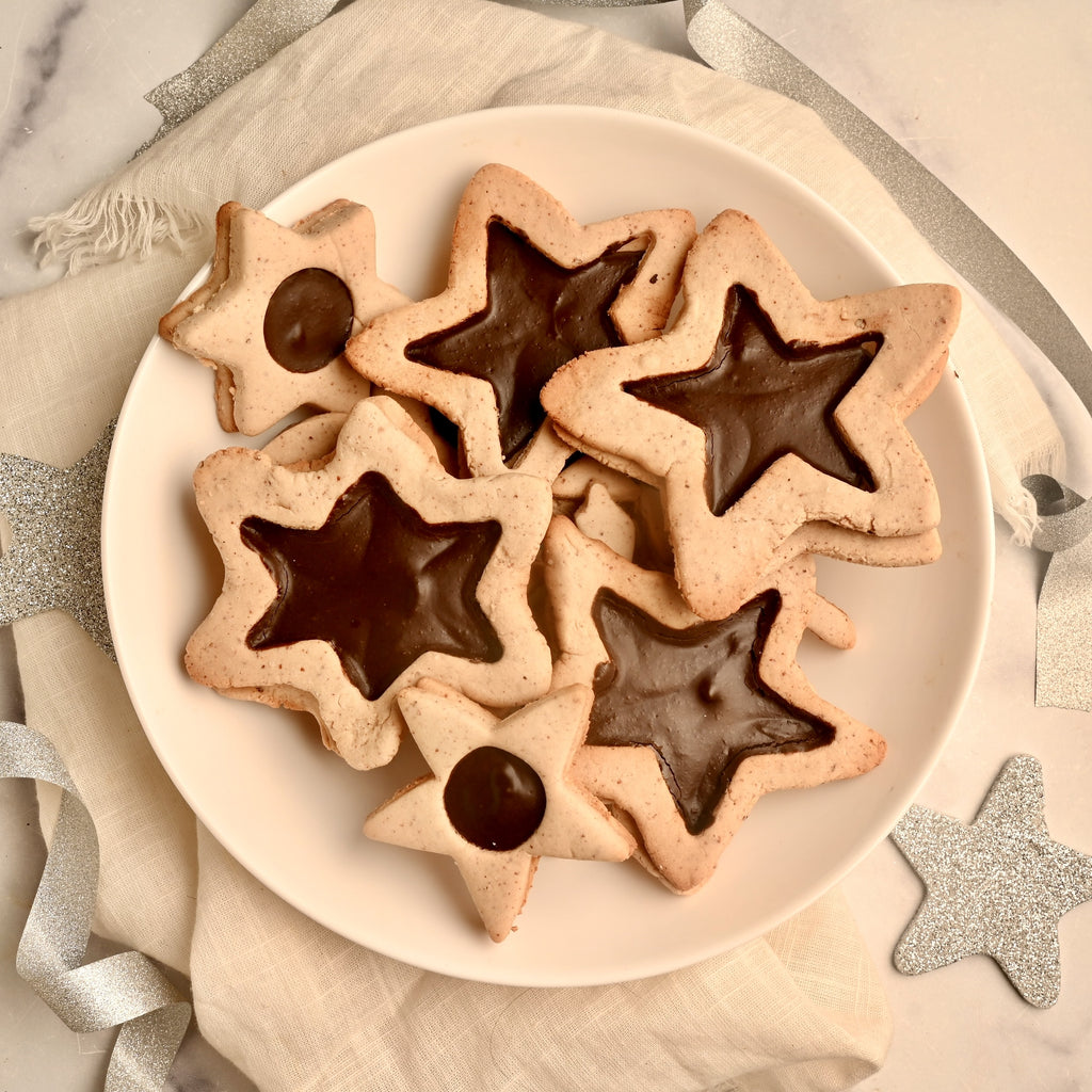 A plate of star shaped cookies with chocolate in the middle