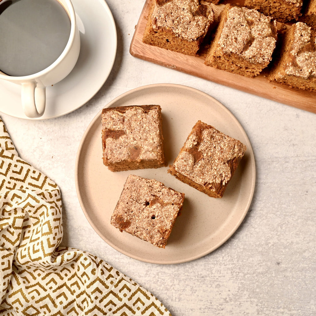 A plate of pumpkin coffee cake next to a mug of black coffee