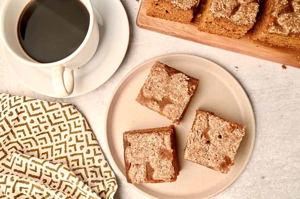 A plate of pumpkin coffee cake slices next to a mug of black coffee