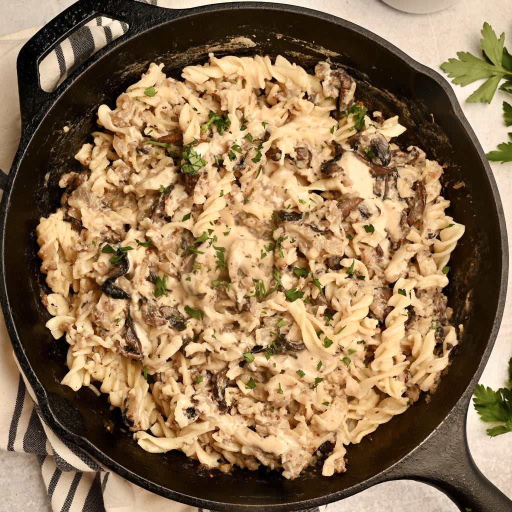 A close up of noodles in a cream sauce in a black cast iron skillet