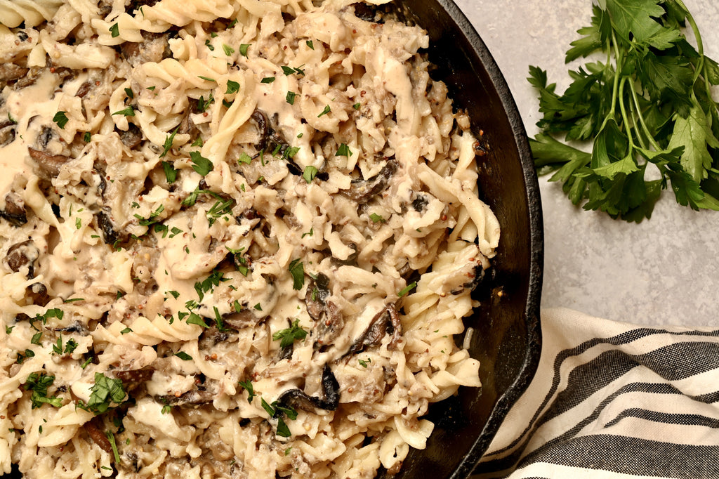 A close up of pasta and sliced mushrooms in a cream sauce