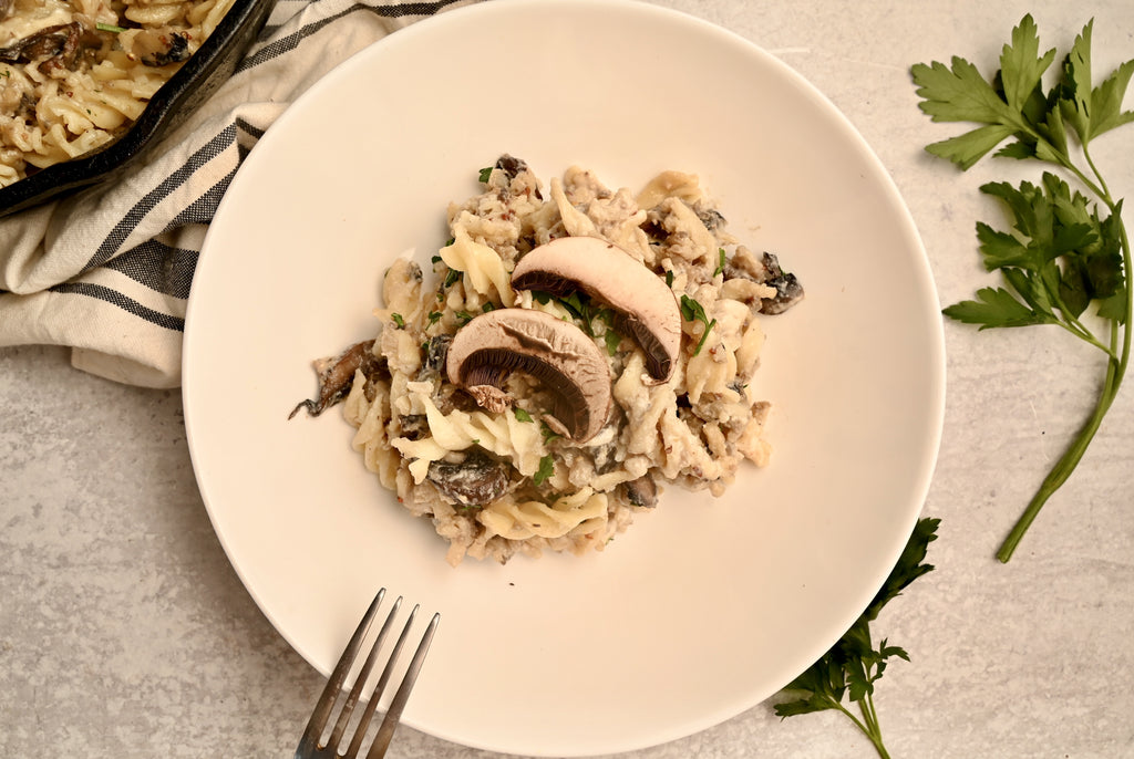 A plate of noodles and mushrooms with a fork