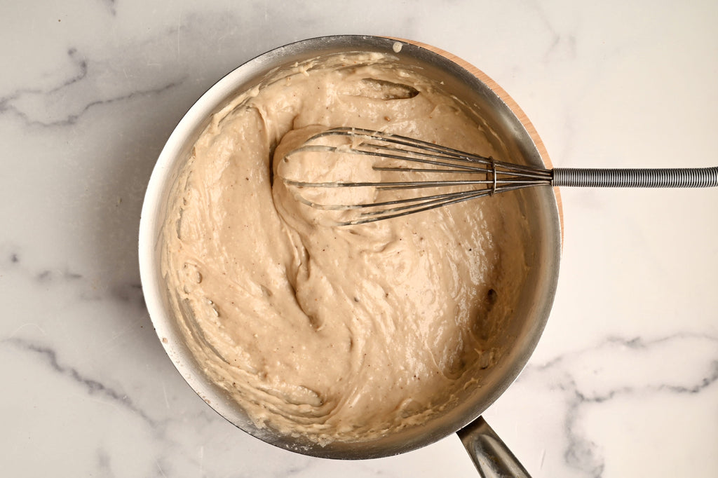 A bowl of raw bread dough with a whisk