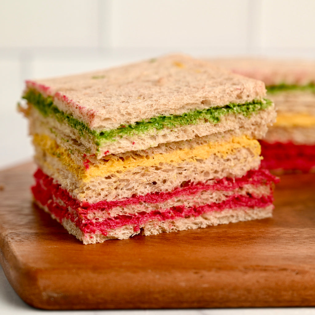 A stacked sandwich with rainbow colored vegetables as filling