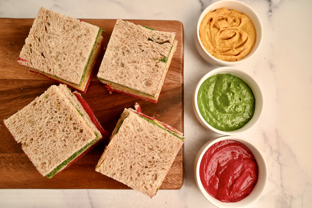 A wooden cutting board with finger sandwiches on it