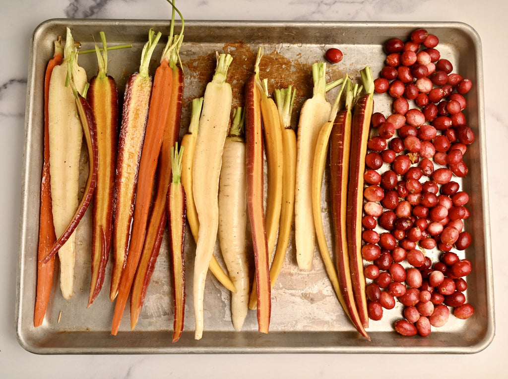 Raw carrots sliced in half on a roasting tray