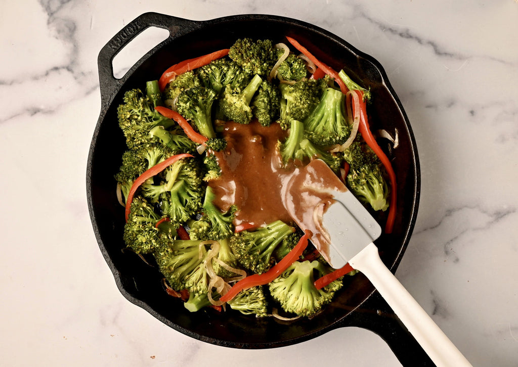a skillet with brocolli and a stir fry sauce