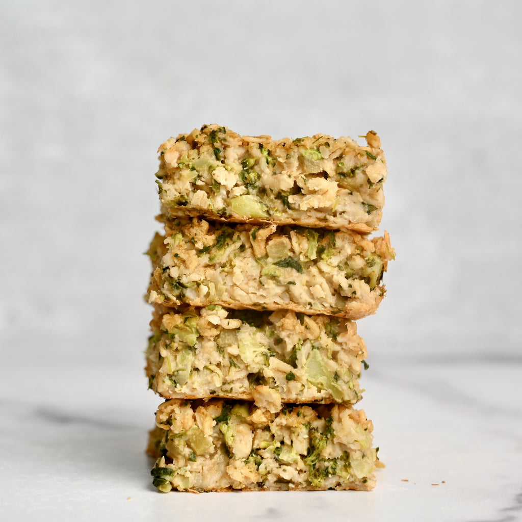 A close up of a stack of oatmeal squares filled with green vegetables