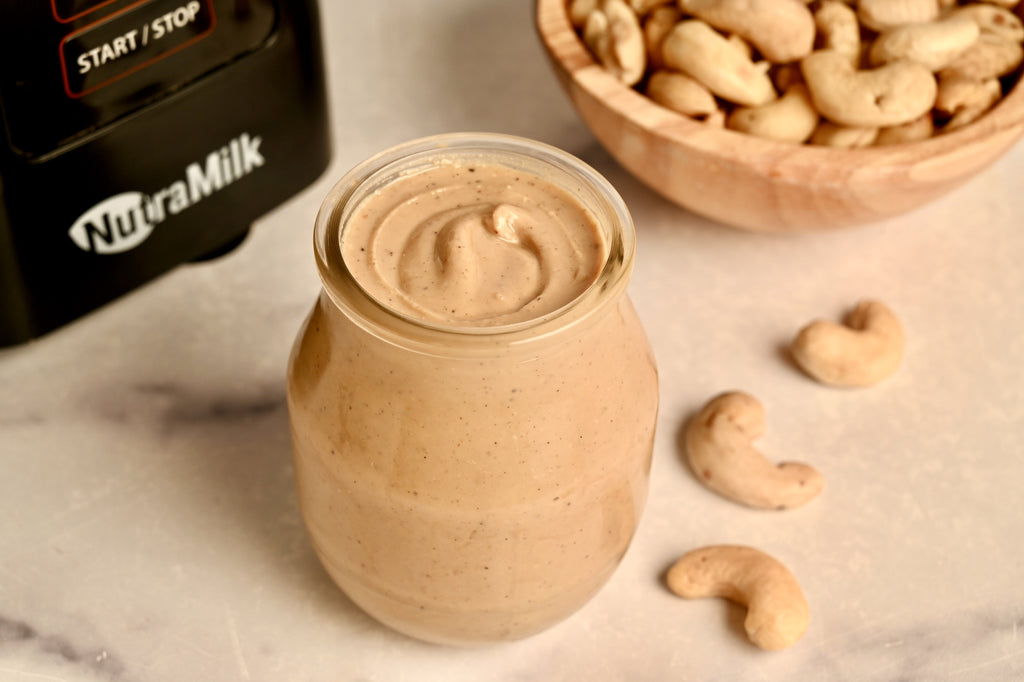 A clear glass far filled with cashew butter made from The NutraMilk