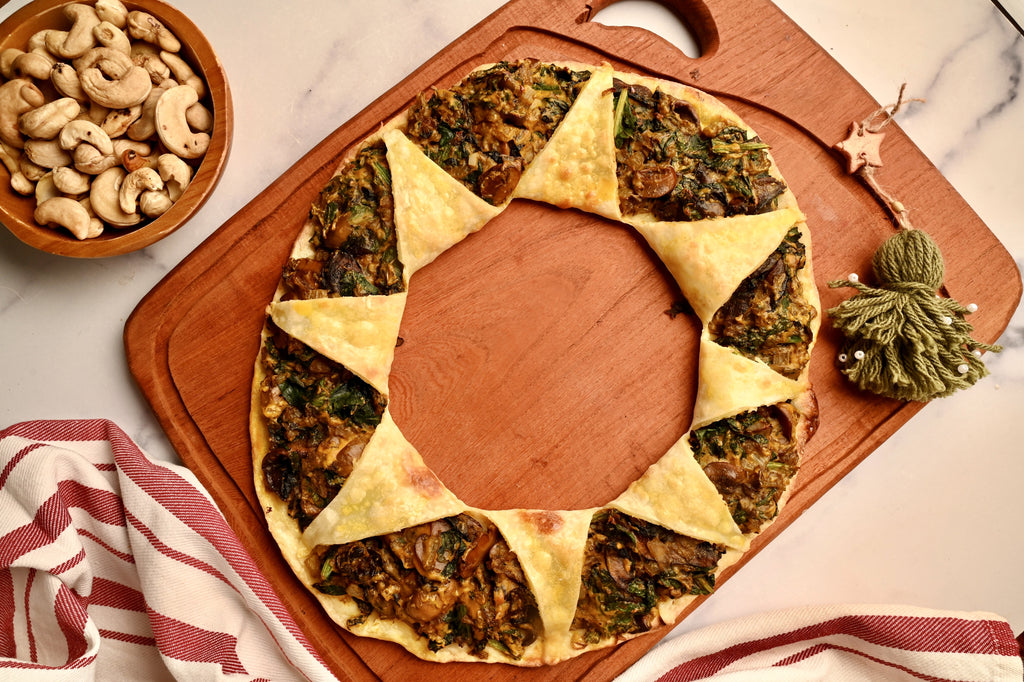 A wooden cutting board with a mushroom spinach pizza ring on it