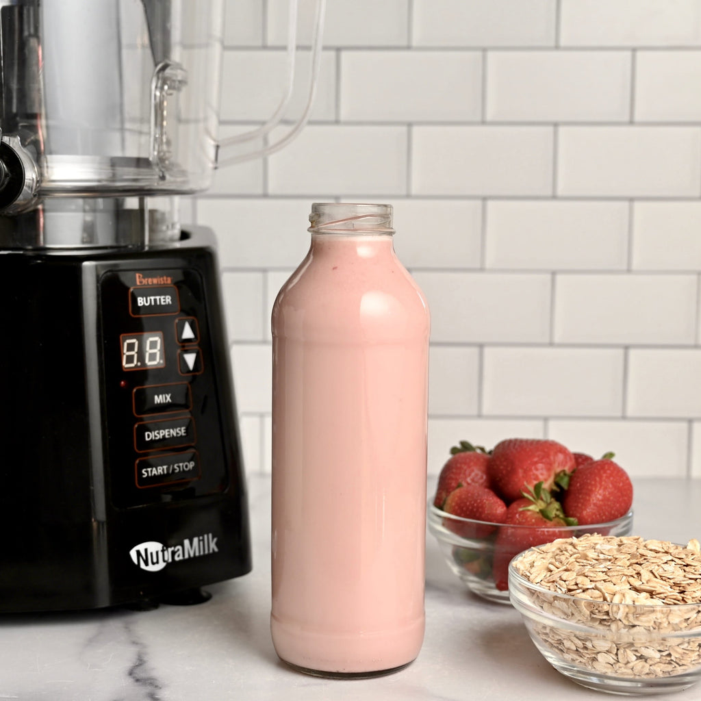 The NutraMilk with a glass of fresh strawberry oat milk