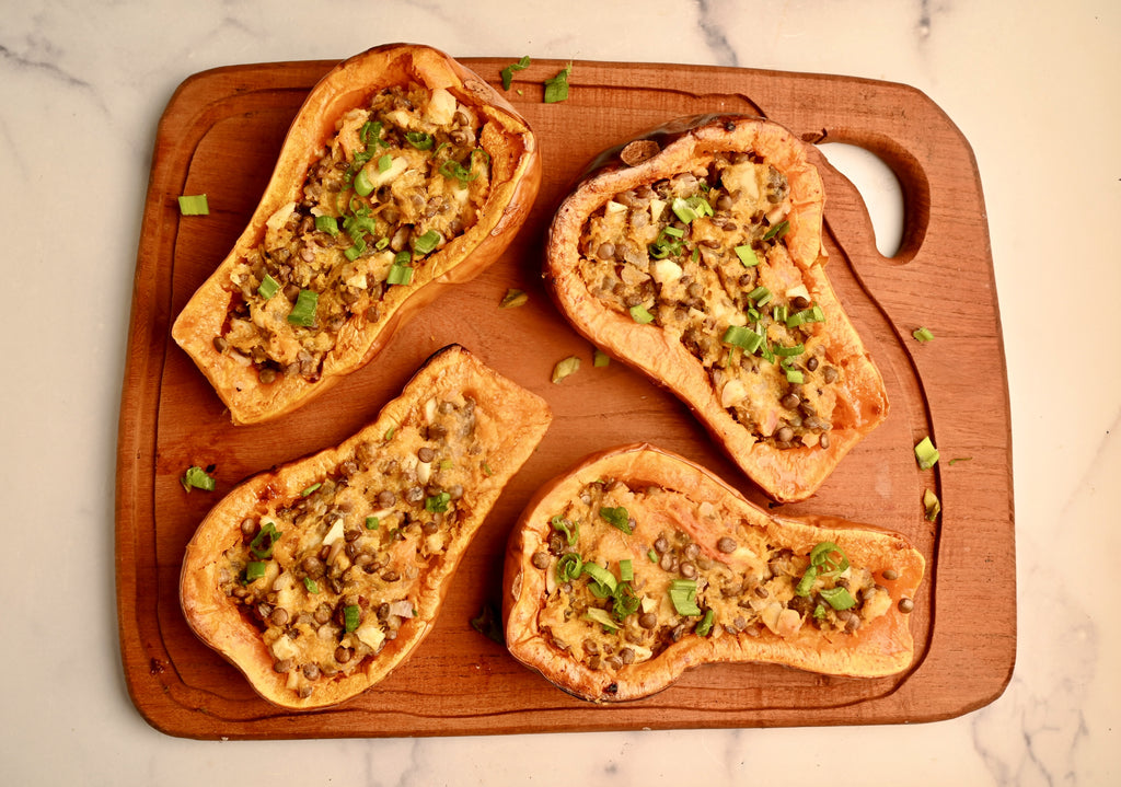 Stuffed butternut squash halves on a wooden serving tray