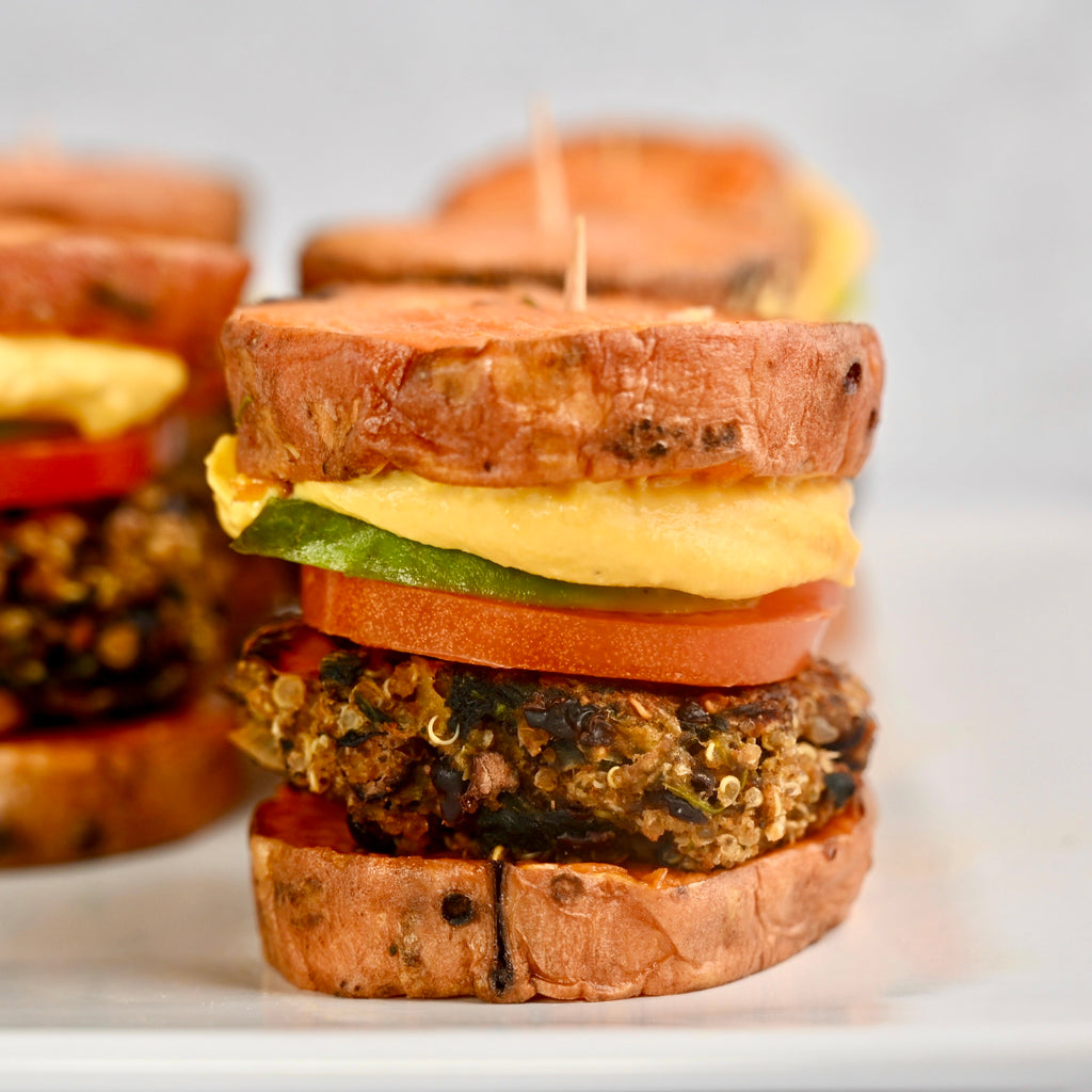 A close up of plant based burgers between two sweet potato slices