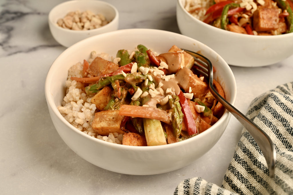 A bowl of tofu and asparagus stir fry in a white bowl