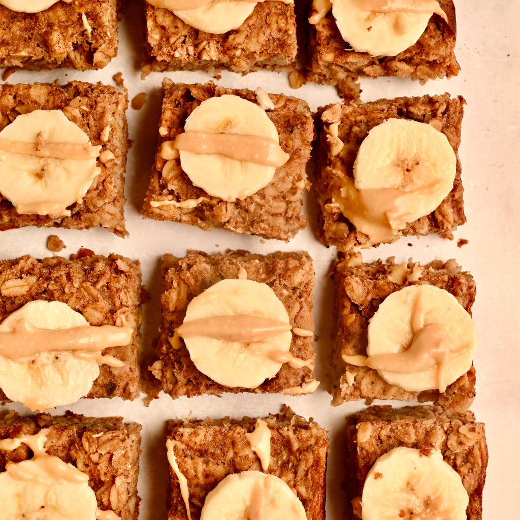 A close up of oatmeal squares with banana slices and nut butter