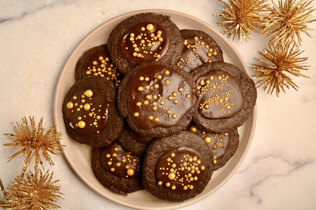 A plate of double chocolate cookies with gold sprinkles in the center