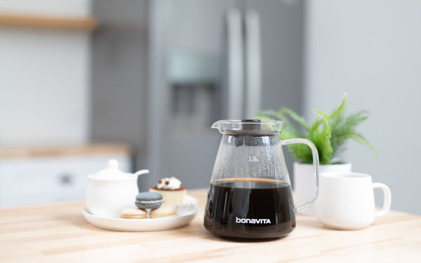 A glass carafe with coffee sits atop a modern kitchen countertop.