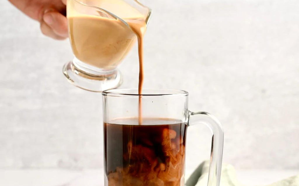 A man is pouring non-dairy creamer into a cup of coffee.