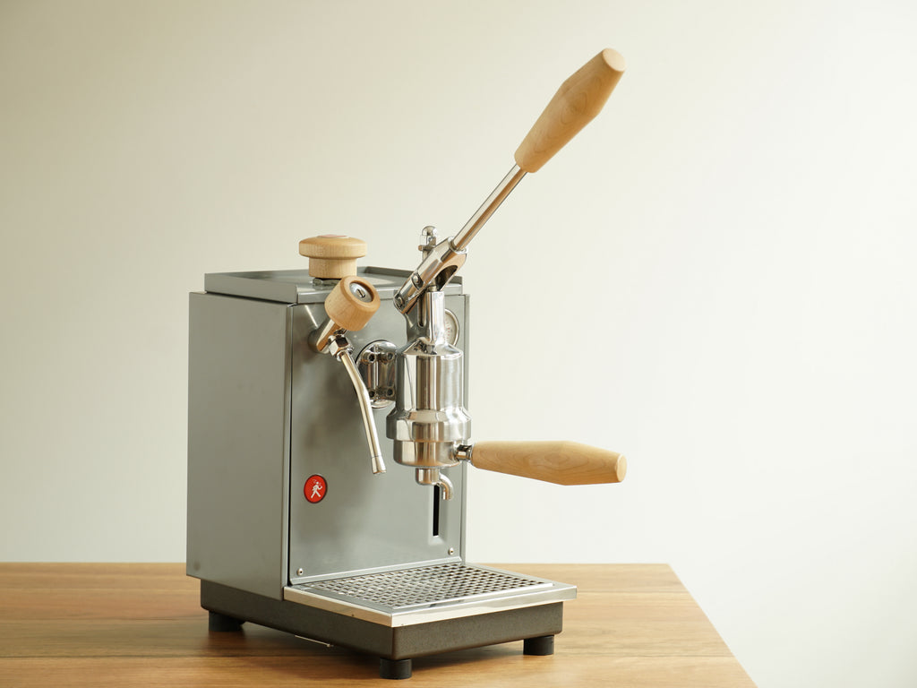 A Specht Olympia Express Cremina lever espresso machine with maple wood accents.