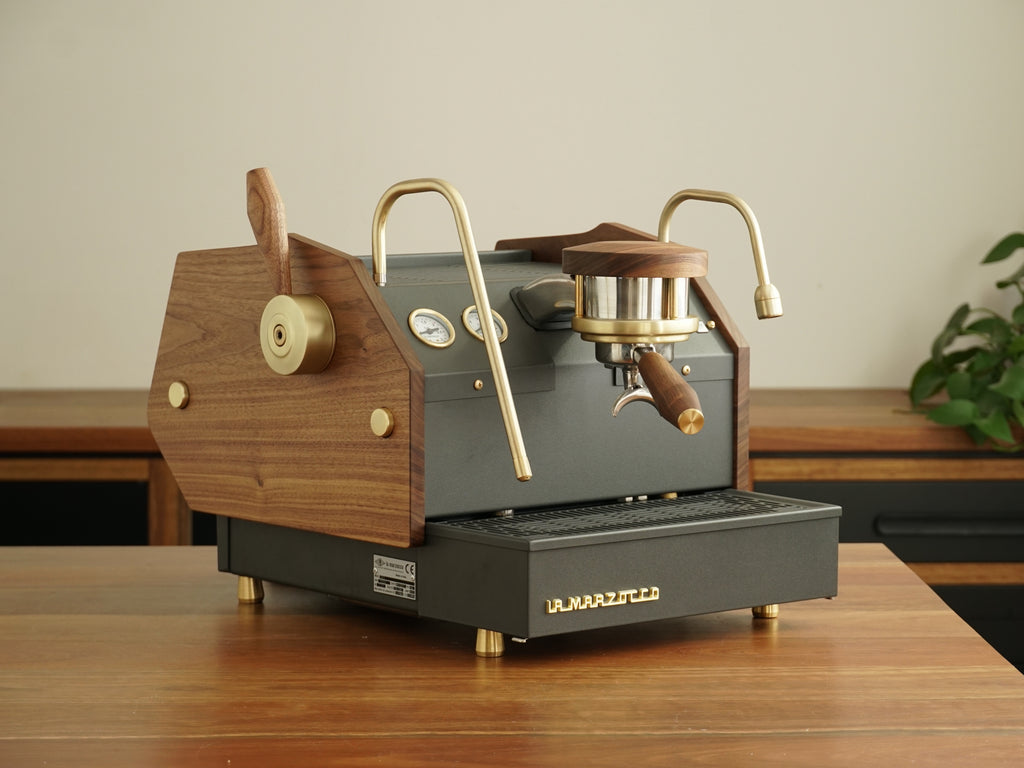 The Specht GS3 Monument home espresso machine with brushed brass and walnut wood accents.