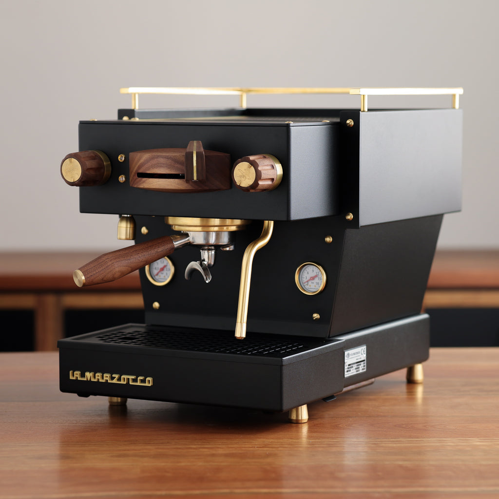 A black, Specht La Marzocco Linea Mini home espresso machine with polished brass and walnut wood accents.