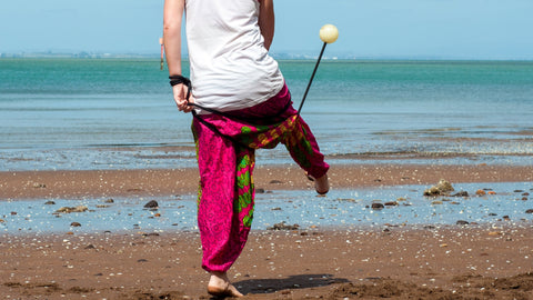 A person spins rope dart on the beach