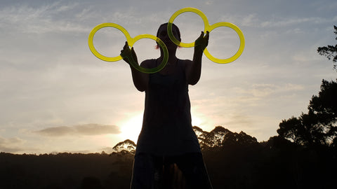 The silhouette of a person spinning 8 rings against a sunset sky