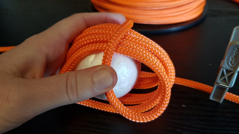 Orange rope is wrapped around a ball to make a monkey fist