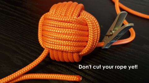 The finished orange DIY monkey fist sits on a black desk