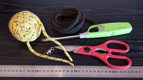 A monkey fist and other materials used to make a DIY rope dart sit on a black desk