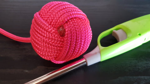 A close up of a pink monkey fist showing where to cut the rope to make DIY poi