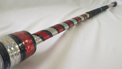 A close up of a red, black, and silver day flow practice spin staff